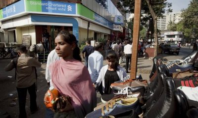 Pedestrians walk by a Standard Chartered Mumbai