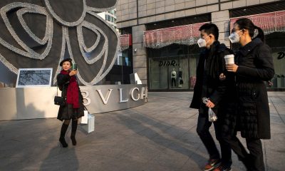 Pedestrians walk past a shopper taking a selfie; China's generation z;