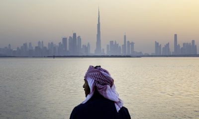 An Emirati man looks out from the Dubai Creek Habour Development towards the Burj Khalifa tower, center, and other skyscrapers in Dubai, United Arab Emirates, UAE