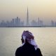 An Emirati man looks out from the Dubai Creek Habour Development towards the Burj Khalifa tower, center, and other skyscrapers in Dubai, United Arab Emirates, UAE